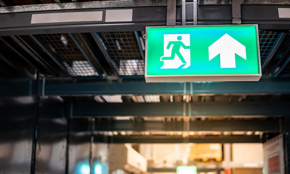 Green emergency exit sign or fire exit sign showing the way to escape with arrow symbol.