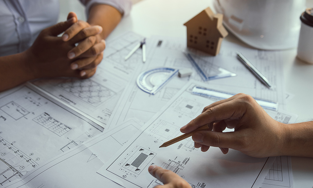 The partnership engineering man or co-workers working on a project and discussing together with looking at blueprint paperwork.